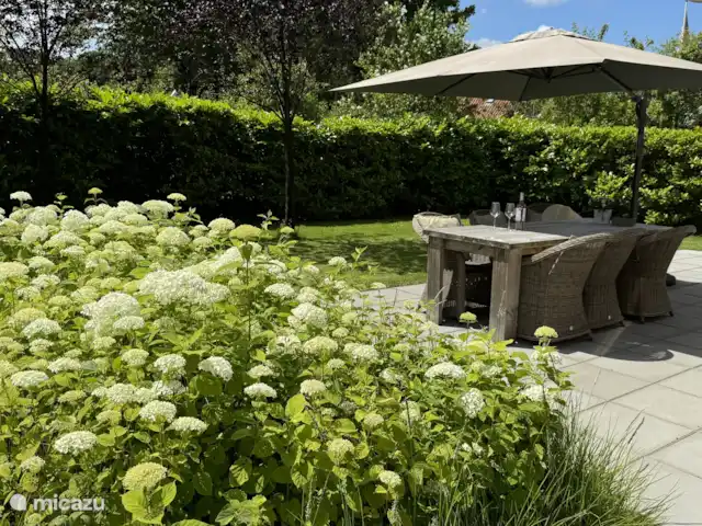 Aan de achterzijde grens de tuin (600m2) en het terras aan de living met openslaande tuindeuren.